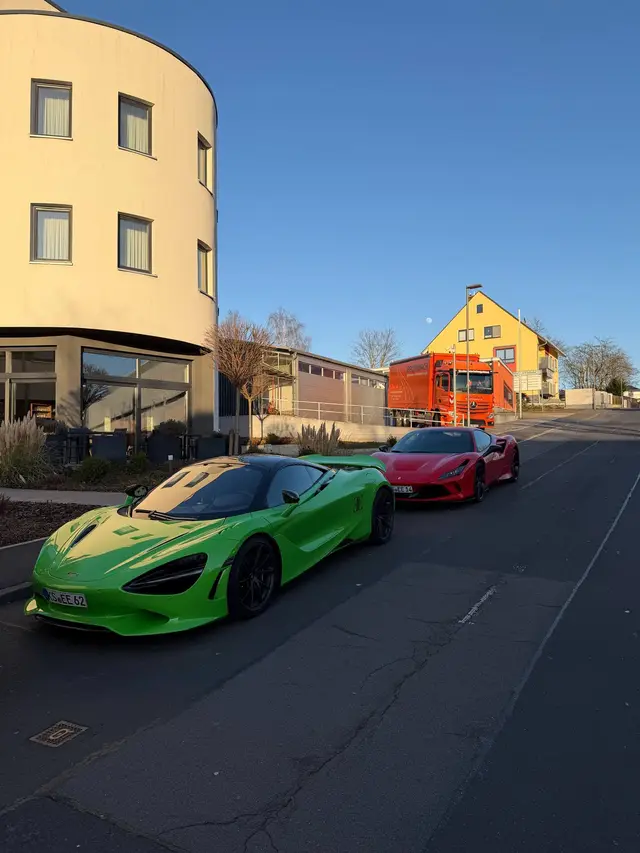 Grüner McLaren und roter Ferrari am Straßenrand