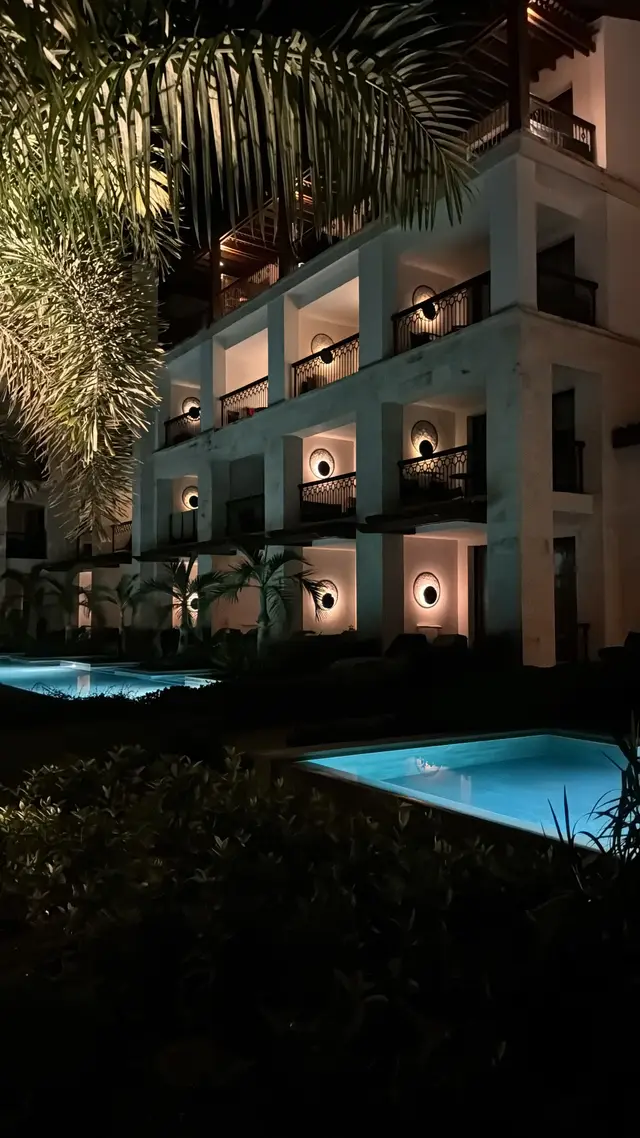 Hotelanlage mit beleuchtetem Pool am Abend